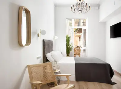 a bedroom with a bed and a mirror and chairs at La Maison de Barcelone in Barcelona