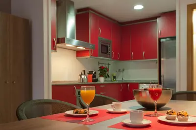 a kitchen with red cabinets and a table with glasses of orange juice at MH Apartments Gracia in Barcelona