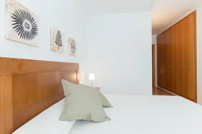a bedroom with a white bed with a wooden headboard at Sweet Apartments in Sant Pere de Ribes