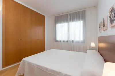 a white bedroom with a bed and a window at Sweet Apartments in Sant Pere de Ribes