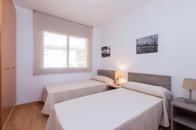 two beds in a white room with a window at Sweet Apartments in Sant Pere de Ribes