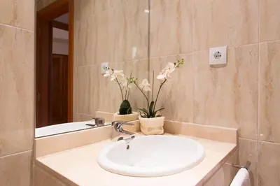 a bathroom with a sink and a mirror and flowers at Sweet Apartments in Sant Pere de Ribes
