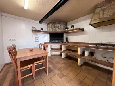 a large kitchen with a wooden table and chairs at La Bruixa Rural in Dosríus