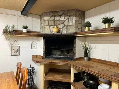 a kitchen with a stove and a stone fireplace at La Bruixa Rural in Dosríus