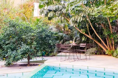 a table and chairs next to a pool with trees at Aspasios Garden Apartments in Barcelona