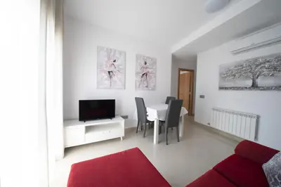 a white living room with a table and a tv at Apartamento centro histórico en Manresa in Manresa