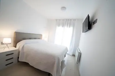 a white bedroom with a bed and a window at Kisa Apartments de Manresa in Manresa