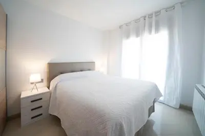 a white bedroom with a white bed and a window at Kisa Apartments de Manresa in Manresa