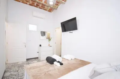 a white room with a bed with a flat screen tv at Apartahotel Casa Batito in Hospitalet de Llobregat