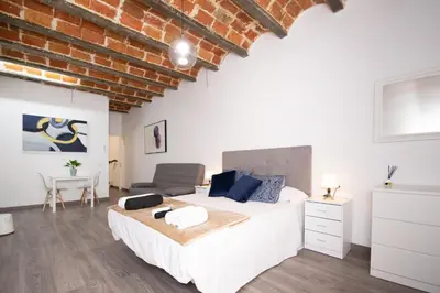 a bedroom with a white bed and a brick wall at Apartahotel Casa Batito in Hospitalet de Llobregat