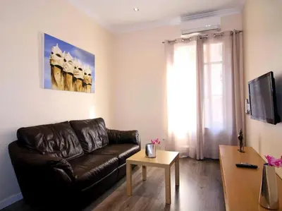 a living room with a leather couch and a table at ClassBedroom Eixample Free Apartments in Barcelona