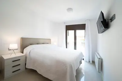 a white bedroom with a bed and a tv at Apartamento Arbones de Manresa in Manresa