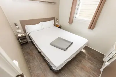 a small bedroom with a white bed and a window at Camping Bellsol Pets in Pineda de Mar
