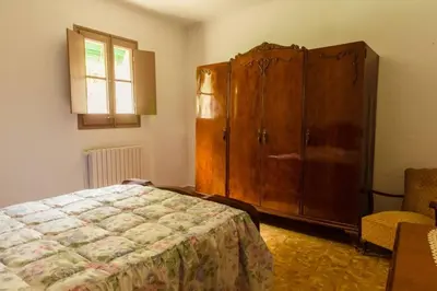 a bedroom with a bed and a large wooden cabinet at Masia Can Castanyola in Marganell