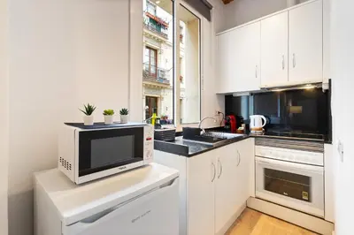 a kitchen with white cabinets and a microwave at Lodging Apartments Beach Studio 11 in Barcelona