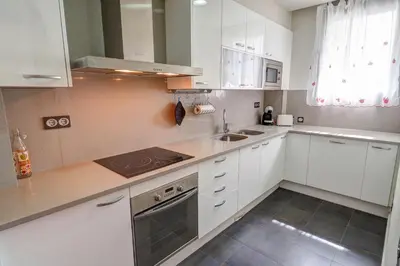 a kitchen with white cabinets and a stove top oven at Seaside April Apartment by Hello Homes Sitges in Sitges
