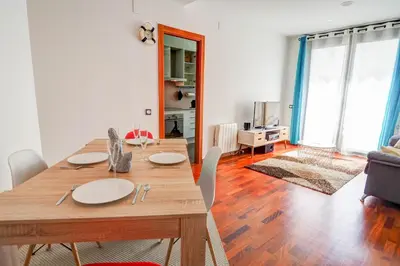a dining table and chairs in a living room at Seaside April Apartment by Hello Homes Sitges in Sitges
