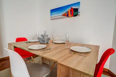 a dining room table with red chairs and a wooden table at Seaside April Apartment by Hello Homes Sitges in Sitges
