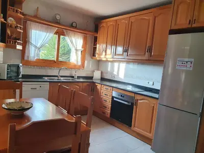 a kitchen with wooden cabinets and a table and a refrigerator at Vino que del Cielo Vino. Alt Penedès (País del Cava) Barcelona in San Quintín de Mediona