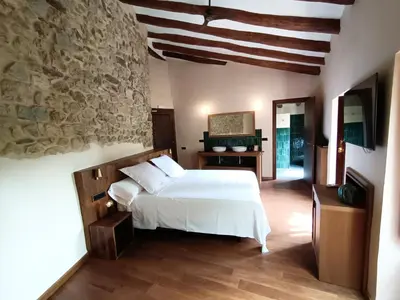 a bedroom with a white bed and a stone wall at Hotel Montrubí 1771 - Slow Winery Hotel - Adults only in Font-Rubí