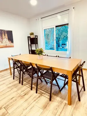 a wooden table and chairs in a room with a window at Apartamentos Tarradellas Sants Estació in Barcelona