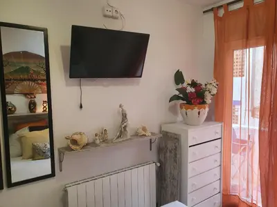 a room with a television on a wall with a dresser at APARTAMENTO CON OFICINA Y VISTAS AL MAR in Sitges