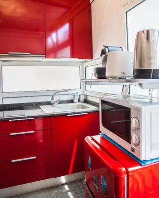 a kitchen with red cabinets and a microwave on a red table at Estudio Maignon in Barcelona