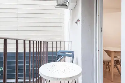 a white table and a blue chair on a balcony at Homenfun Barcelona Gracia in Barcelona