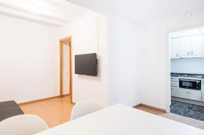 a white room with a kitchen and a table and chairs at Homenfun Barcelona Gracia in Barcelona