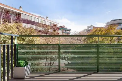 a balcony with a green fence and a potted plant at ApartsNouBcn Equador Les Corts in Barcelona