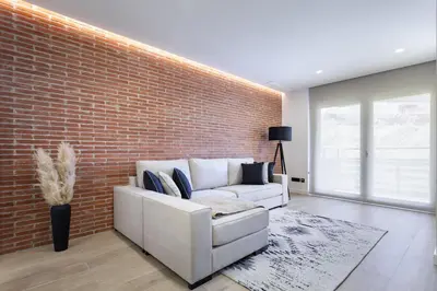 a living room with a white couch against a brick wall at ApartsNouBcn Equador Les Corts in Barcelona