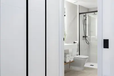 a white bathroom with a shower and a toilet at ApartsNouBcn Equador Les Corts in Barcelona