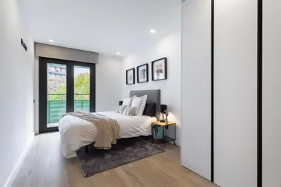 a white bedroom with a bed and a window at ApartsNouBcn Equador Les Corts in Barcelona