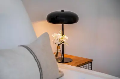 a lamp sitting on a table with a vase of flowers at ApartsNouBcn Equador Les Corts in Barcelona