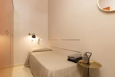 a small bedroom with a bed and a table at ApartEasy - Plaza España & Fira in Barcelona