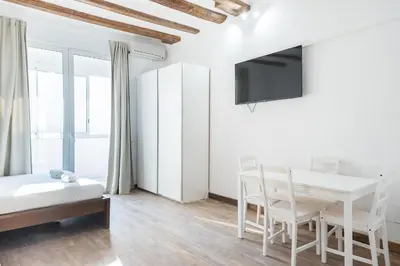a white room with a table and chairs and a tv at Homenfun Barcelona Studio Camp Nou II in Hospitalet de Llobregat