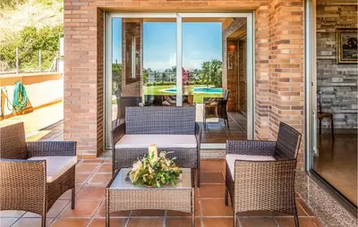 a patio with wicker chairs and a table with a candle at Lovely Home In Sant Cebrià De Vallalta in San Cipriano de Vallalta