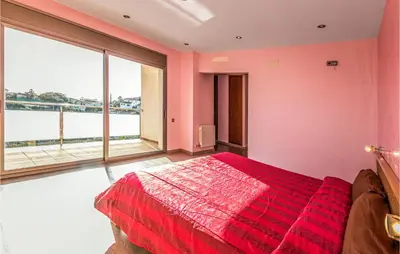a bedroom with a red bed and a large window at Lovely Home In Sant Cebrià De Vallalta in San Cipriano de Vallalta