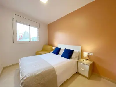 a bedroom with a bed with blue pillows and a window at Terracotta terrace in Barcelona