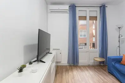 a living room with a tv and a blue couch at Bright 3bdr Near To The Metro in Hospitalet de Llobregat