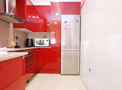 a kitchen with red cabinets and a stainless steel refrigerator at Home Pool and Beach in Cabrera de Mar