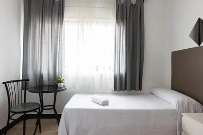 a bedroom with a bed and a table and a window at Pensión Galicia in Canovellas