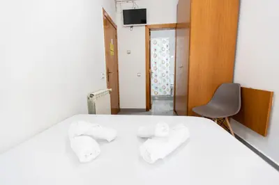 a bedroom with a white bed with two towels at Pensión Galicia in Canovellas