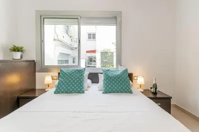 a bedroom with a large white bed with blue pillows at Fragata Sitges Rentals in Sitges