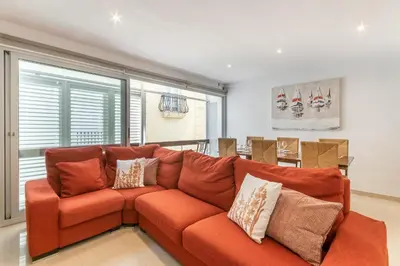 a living room with an orange couch with pillows at Fragata Sitges Rentals in Sitges