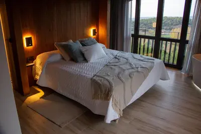 a bedroom with a bed and a large window at Alojamiento MAS EL CASTELL DEL BRULL B&B in El Brull