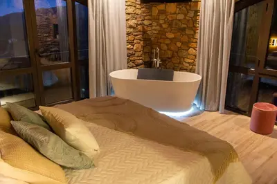 a bedroom with a tub and a bed with pillows at Alojamiento MAS EL CASTELL DEL BRULL B&B in El Brull