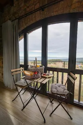 a table and two chairs in a room with windows at Alojamiento MAS EL CASTELL DEL BRULL B&B in El Brull