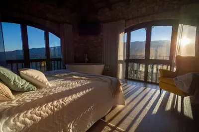 a bedroom with a bed and a tub and windows at Alojamiento MAS EL CASTELL DEL BRULL B&B in El Brull