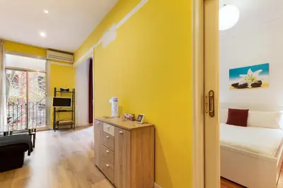 a room with a yellow wall with a bed and a desk at Stay U-nique Apartments Lope de Vega in Barcelona